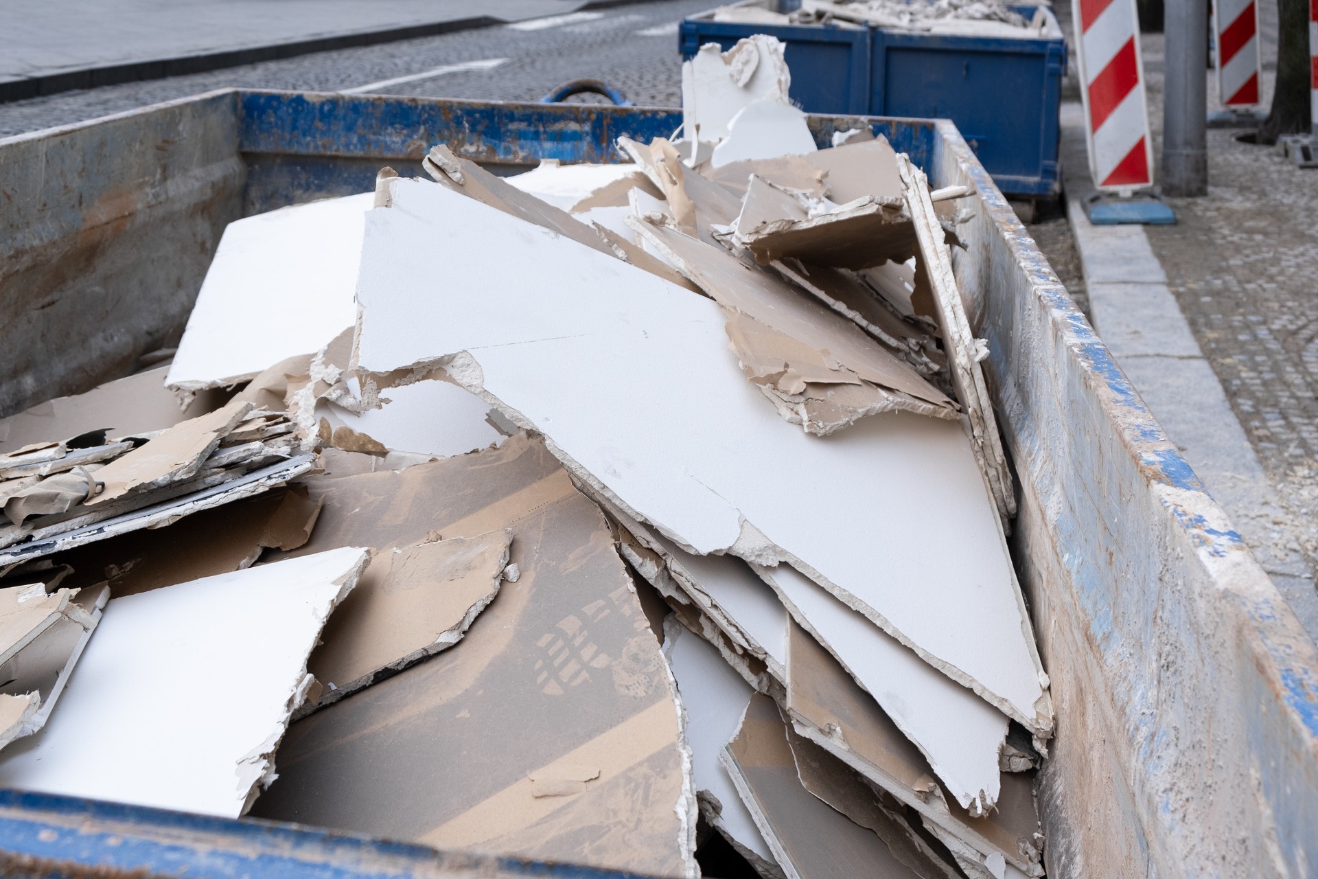 dumpster waste container with construction waste and drywall plasterboard, debris generated during the renovating and reconstruction process.