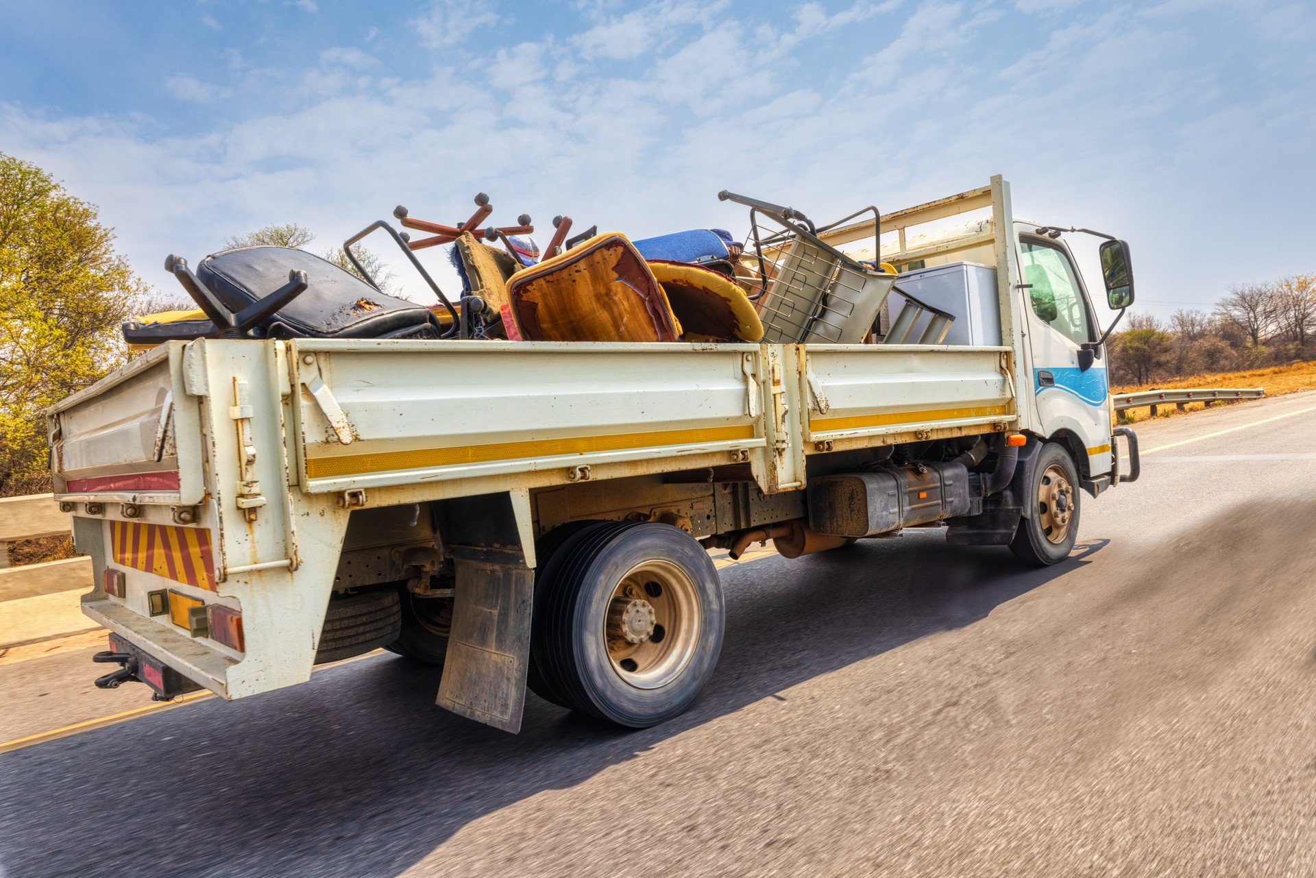 large truck on the city street, carry used broken furniture for recycling